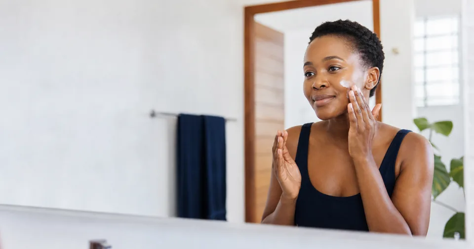 Ghanaian woman applying moisturiser in the morning