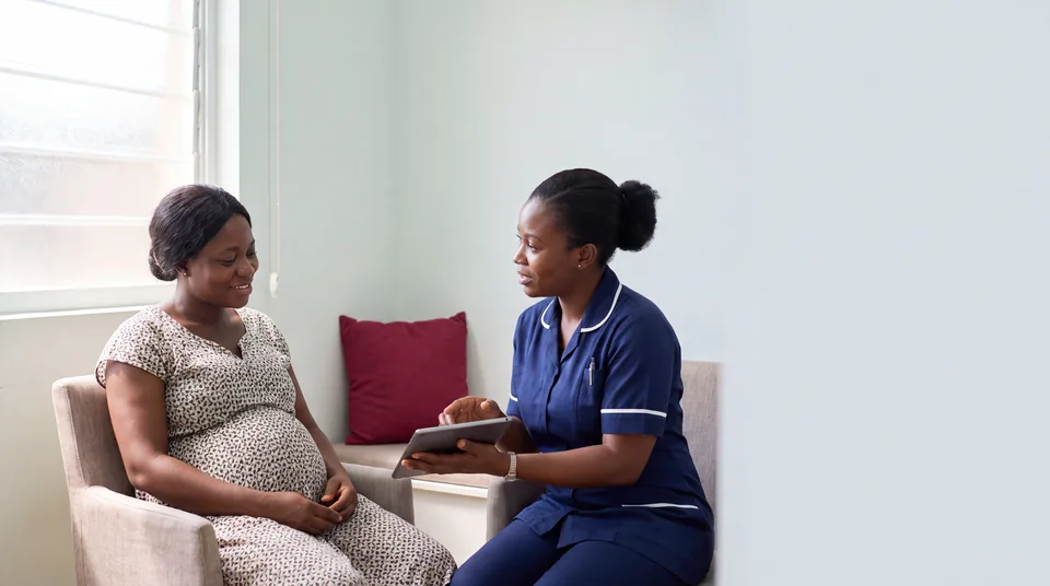 Pregnant Ghanaian woman speaking with a midwife during a consultation